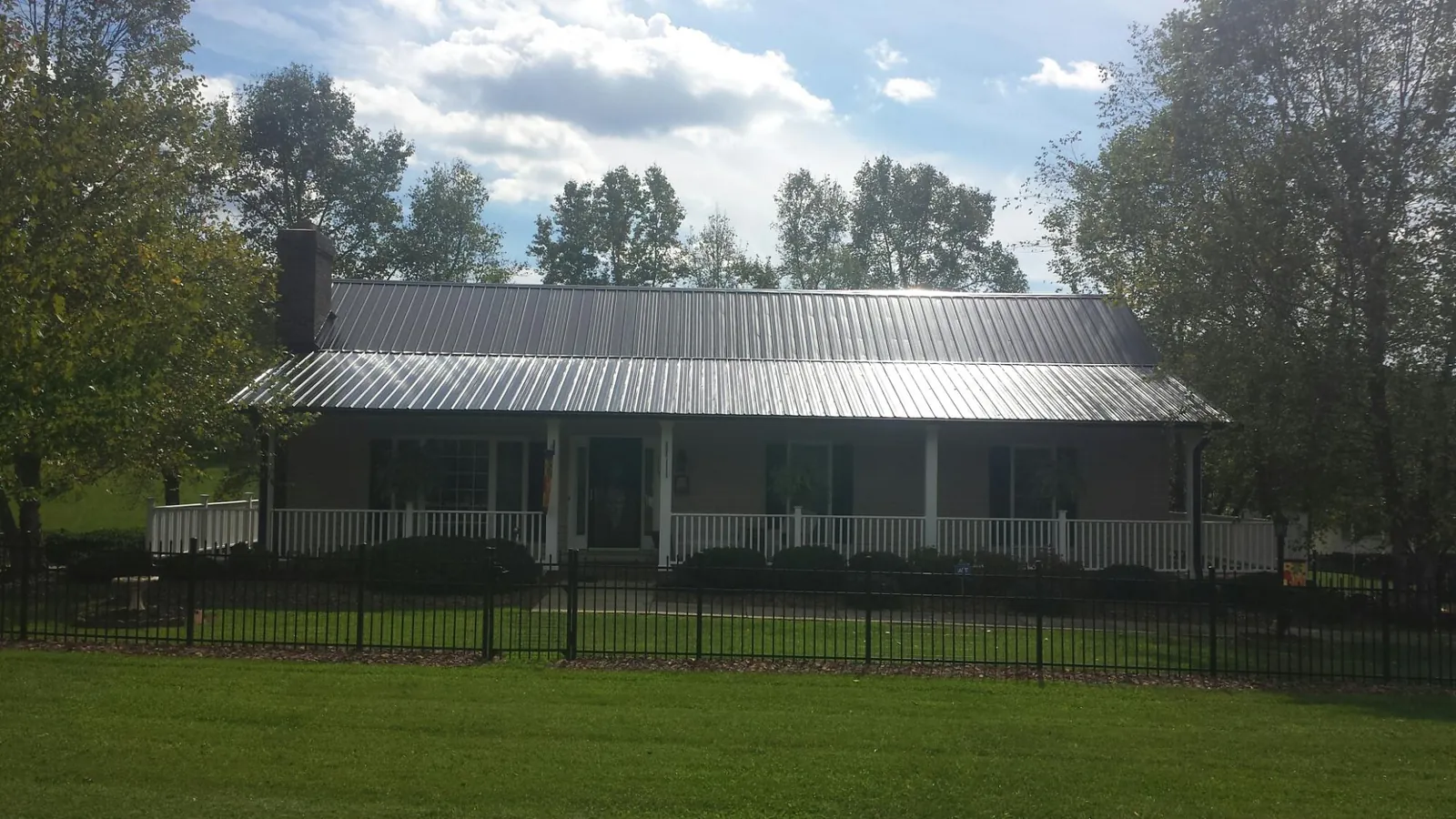 Gray metal roof on a brick ranch with a full width front porch — Gutter Guard Installation work by our crew in Mount Carmel