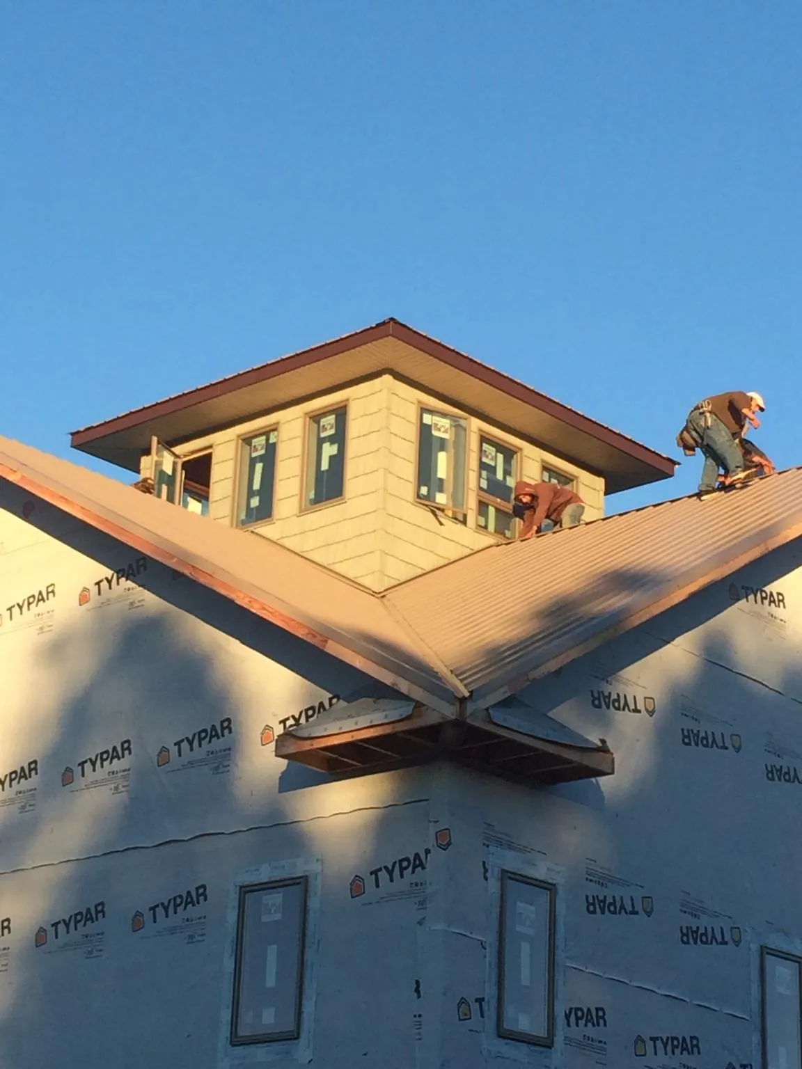 Roofers working around a rooftop cupola on a new metal roof at sunset — Roof Waterproofing in Mount Carmel by Roofing Brothers